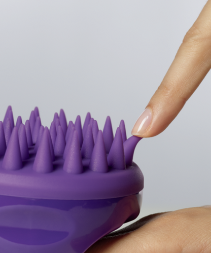 A model tucks a purple denticle of the Dr. Groot Premium Scalp Cleansing Brush